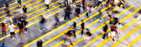 A blurred photo of a busy pedestrian crossing in a city. 