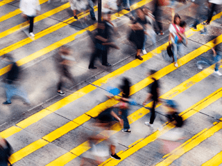 A blurred photo of a busy pedestrian crossing in a city. 