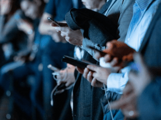 Photo of a group of people focussed in on them holding their phones. 